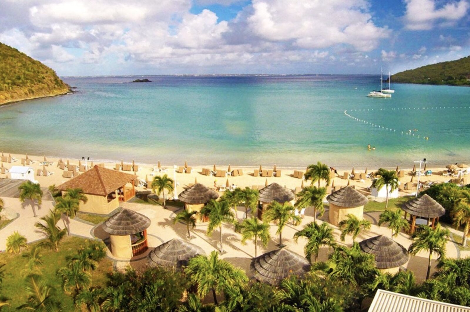 Aerial view of Anse Marcel cove with thatched cabanas and turquoise water